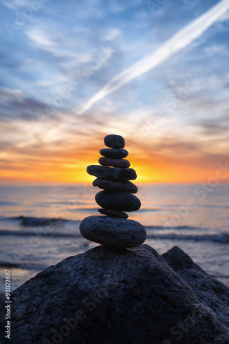 Stable vertical cairn at sunset on the sea