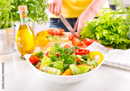 Female hands preparing vegetable salad in the kitchen