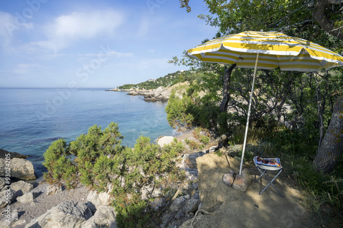 The umbrella and bench on picturesque shore of the black sea.