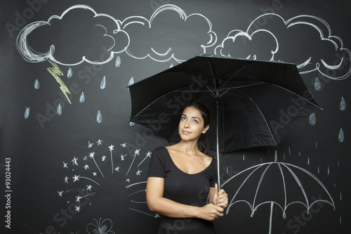 Giovane e bella ragazza si ripara con un ombrello da una pioggia disegnata photo