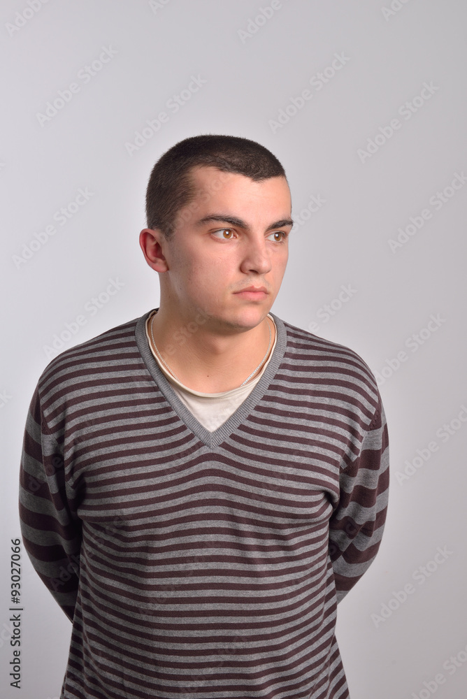 bored young man standing with hands behind his back bored young man standing with hands behind his back
