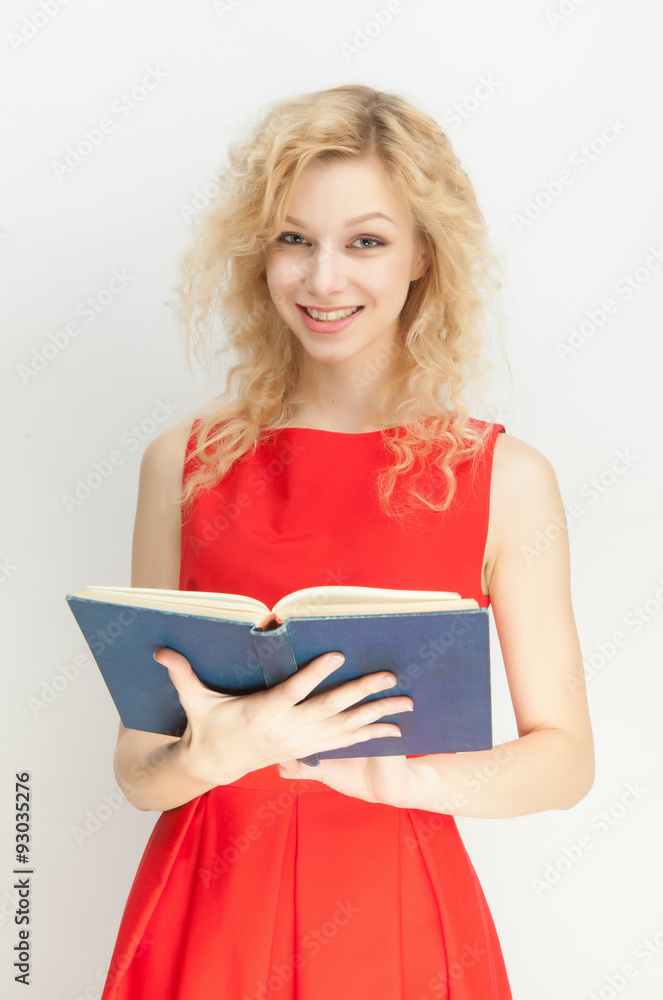 Beautiful blonde in a red dress with a book on a gray background. Beautiful blonde in a red dress with a book on a gray background.