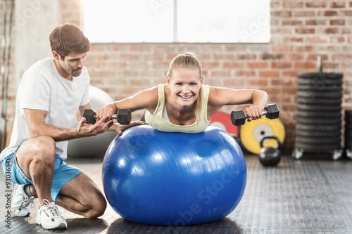 Male trainer helping young woman with the dumbbells 