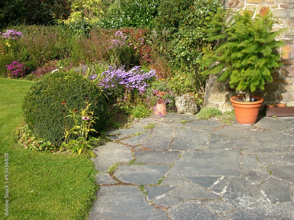 Terrasse mit Platten aus grauem Naturstein und Gartenanlage mit