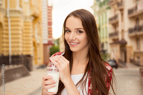 Good-looking girl drinking a milkshake on the street