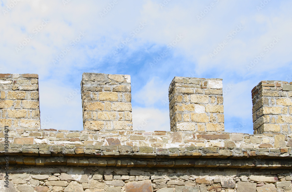  Merlons of ancient stone wall closeup, against blue cloudy sky, Sudak Genoese fortress, Crimea