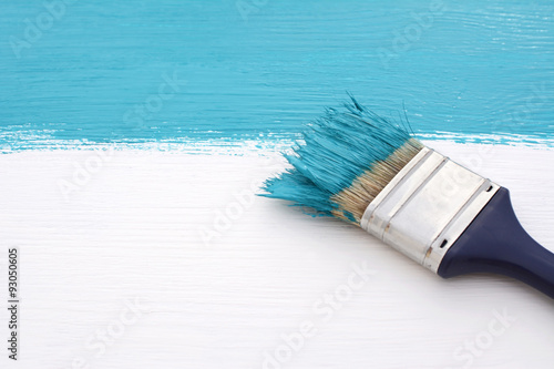Paintbrush with blue paint, painting over white board
