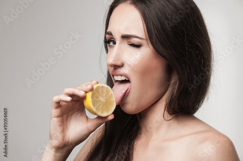 Funny image of young woman eating lemon