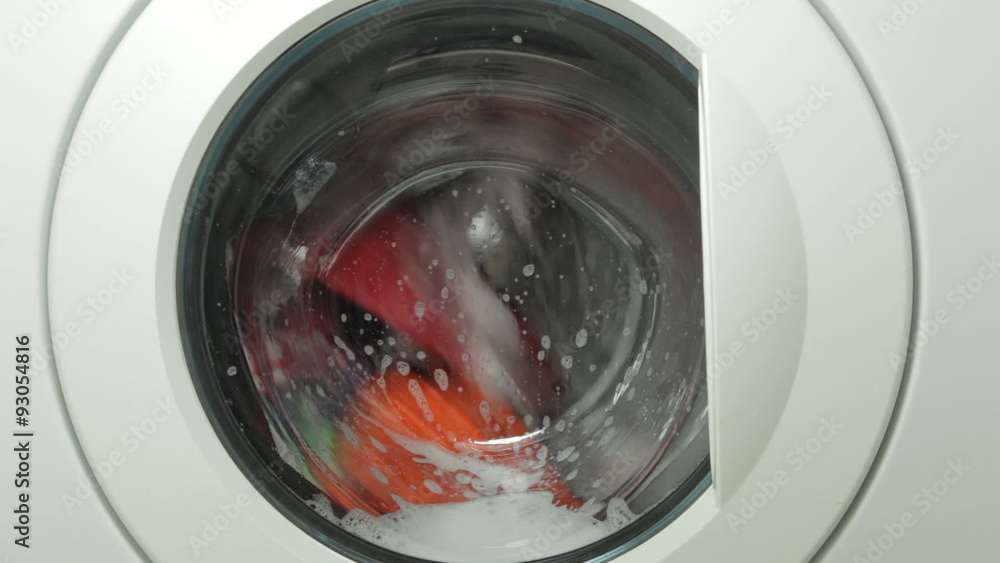 Front-loading washing machine filled with brightly colored tumbling clothing; includes ambient sound.
