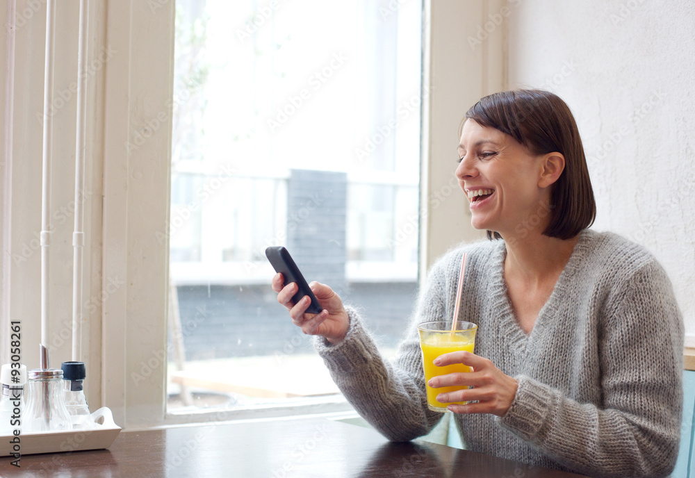 Laughing woman sitting at cafe with mobile phone Laughing woman sitting at cafe with mobile phone