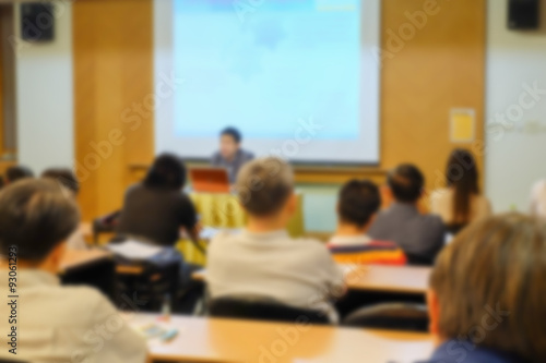 Motion blur of speaker present project with some audience in a meeting room