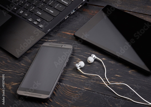 Laptop, smart phone, tablet pc and headset on wooden background