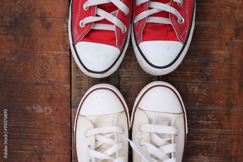 Original Valentine's Day love concept with red and white sneakers. Studio shot on a wooden floor background.