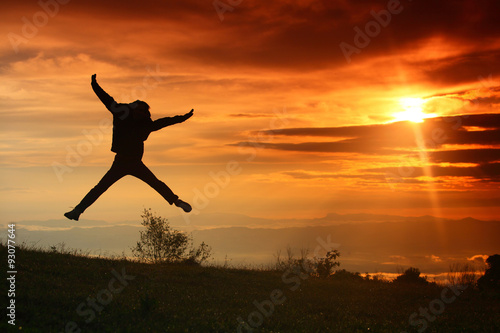 Young man jumps in the sunrise.