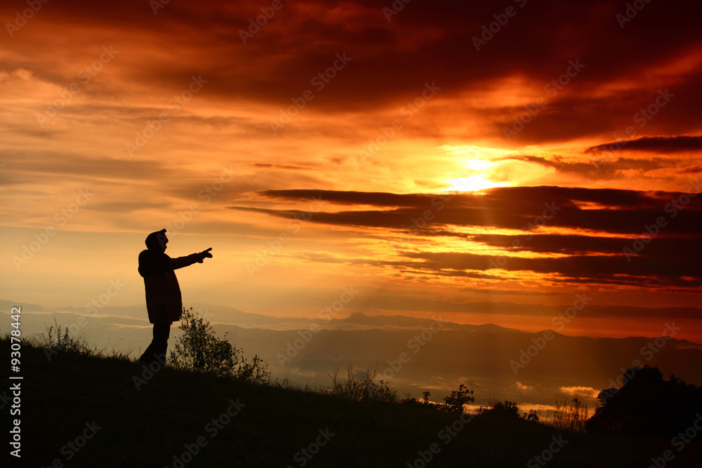 Woman standing pointing up sunrise