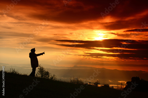 Woman standing pointing up sunrise
