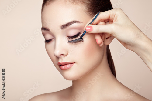 Makeup artist glues eyelashes. Beautiful woman face. Perfect makeup. Beauty fashion. Eyelashes. Cosmetic Eyeshadow