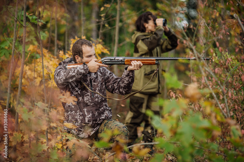 Instructor with woman hunter aiming rifle at firing nature