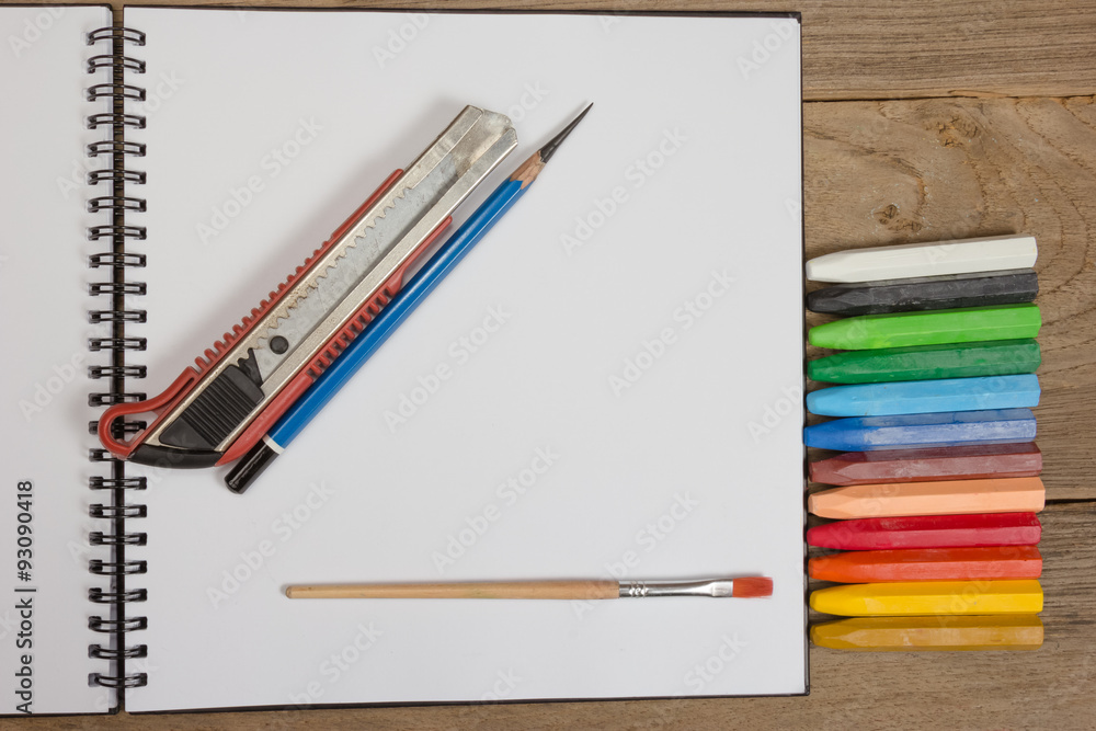 notebook and colorful crayons on wooden background. notebook and colorful crayons on wooden background.