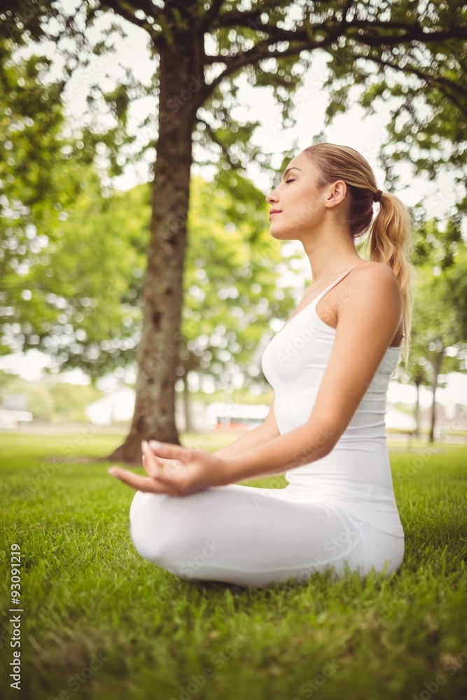 Side view of woman meditating while sitting in lotus pose Side view of woman meditating while sitting in lotus pose