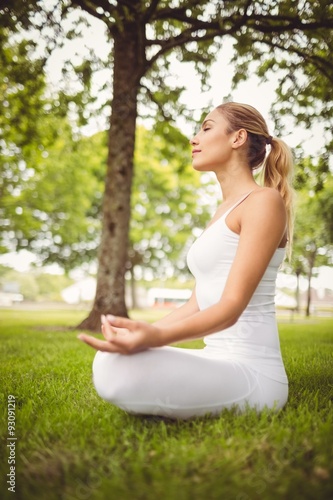 Side view of woman meditating while sitting in lotus pose 