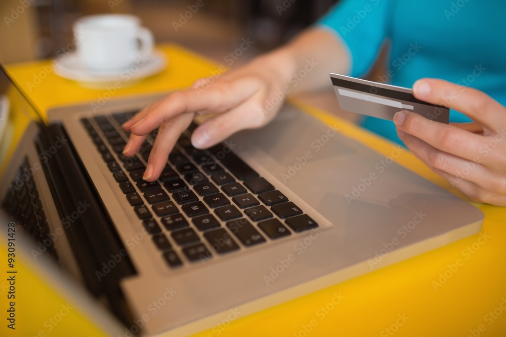 Woman using laptop while holding credit card Woman using laptop while holding credit card