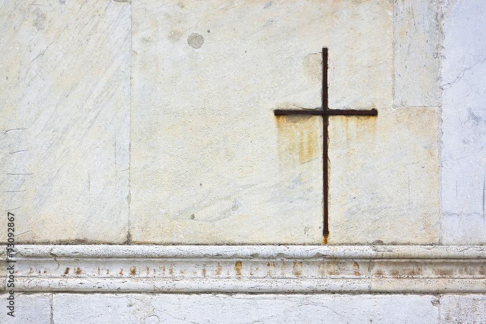 Iron cross snuggled in white stone on a italian facade church