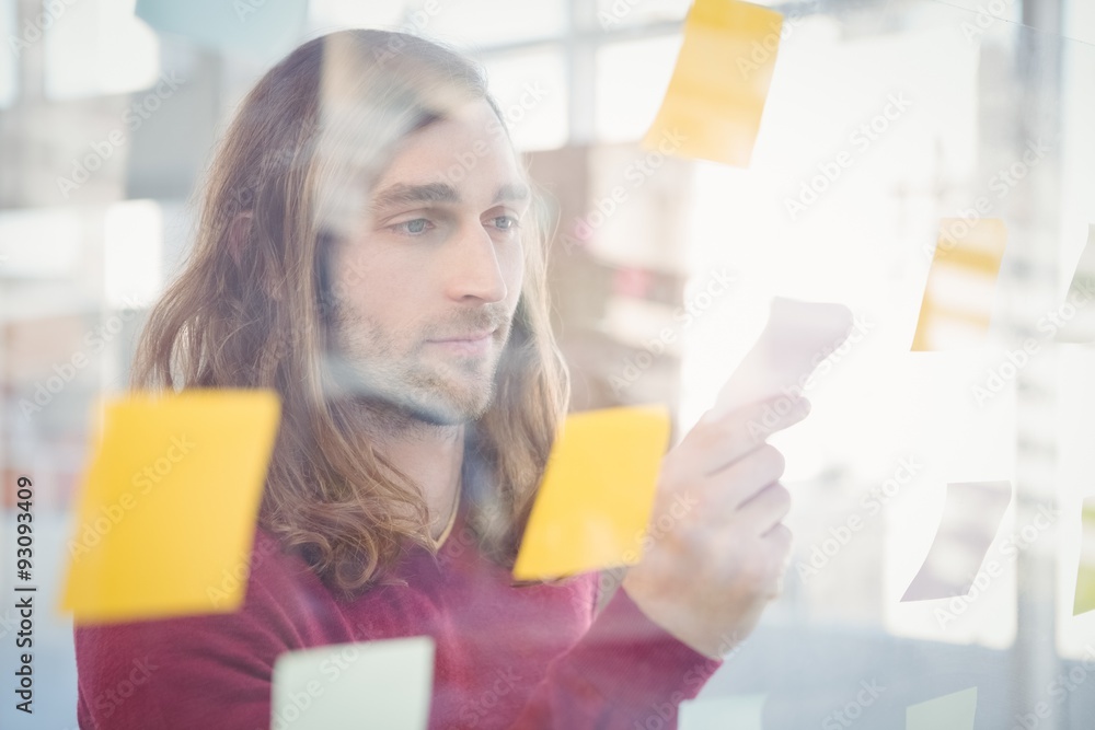 Businessman holding sticky note stuck on glass Businessman holding sticky note stuck on glass