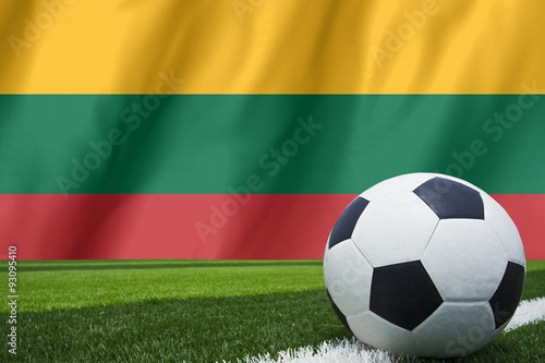 Soccer ball and national flag of Lithuania lies on the green gra