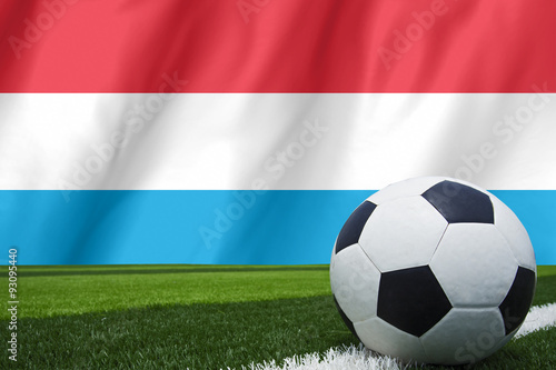 Soccer ball and national flag of Luxembourg lies on the green gr