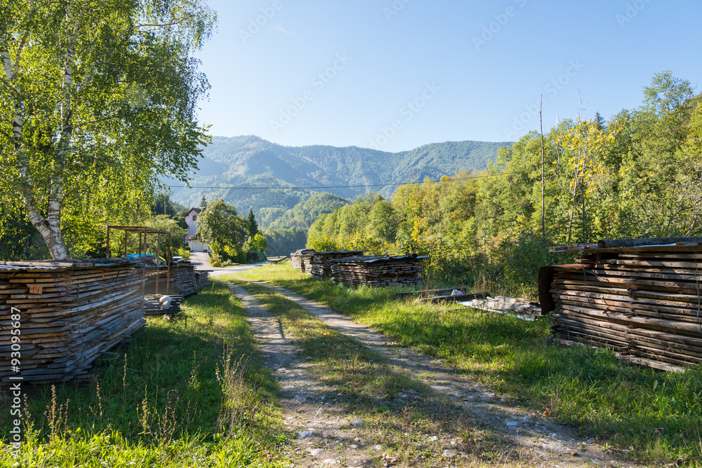 The Ennstal Alps in Upper Austria. The national park Limestone Alps known as Hintergebirge. Stacked wood along a gravel road. Timber economy is a major economic factor in Austria