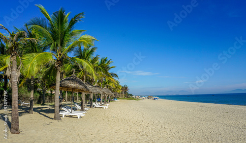 Beautiful sandy beach with parasol and sun lounger : Cua Dai Beach, Hoi An, Vietnam.
