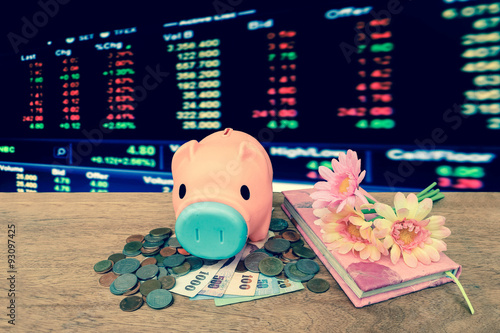 piggy bank with bunch of flower on pile of coins and banknote ,vintage tone