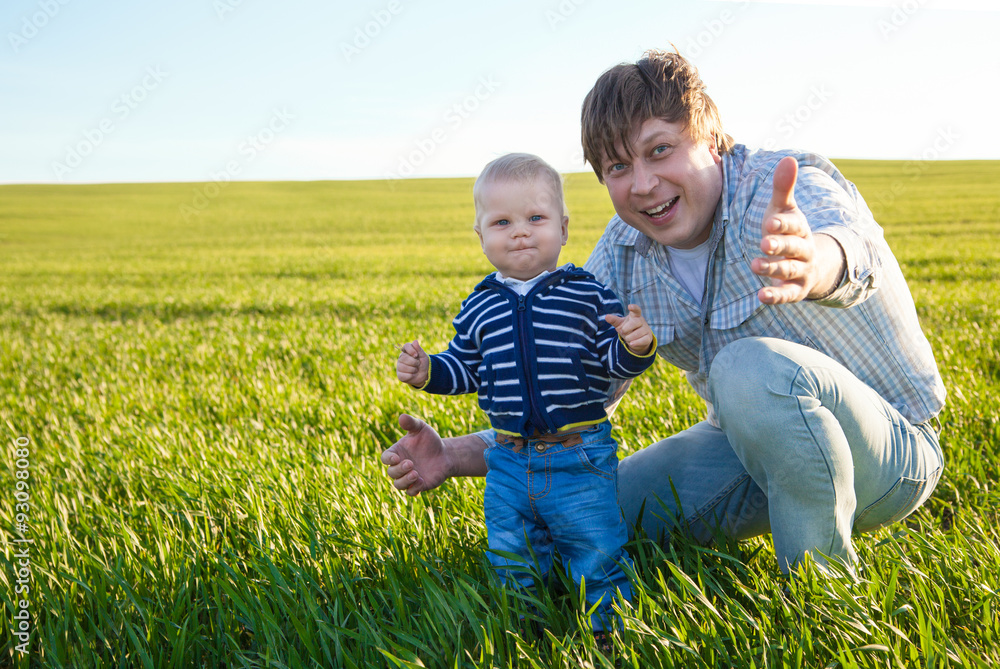Young father and his son having fun, playing on green field Young father and his son having fun, playing on green field