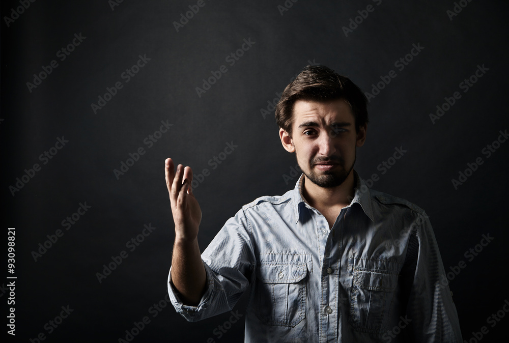 Displeased young man gesturing with one hand