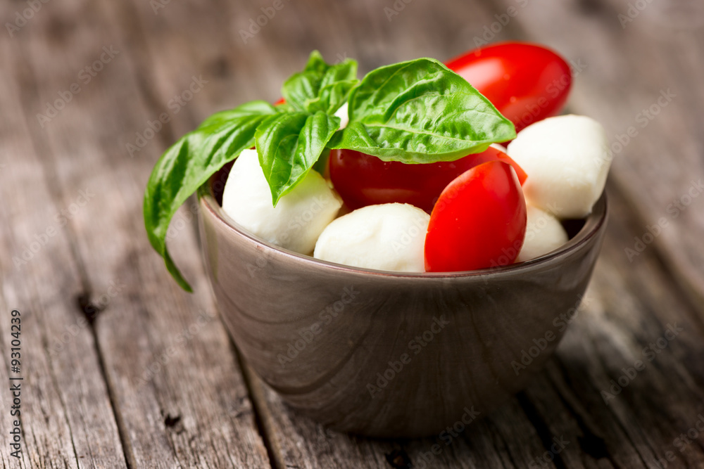 Tomato and mozzarella with basil leaves in bowl Tomato and mozzarella with basil leaves in bowl