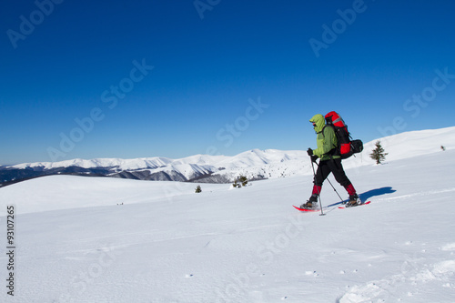 Winter hiking in the mountains on snowshoes with a backpack and tent. © vetal1983