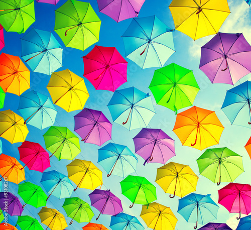 Hanging multicolored umbrellas over blue sky. Abstract background