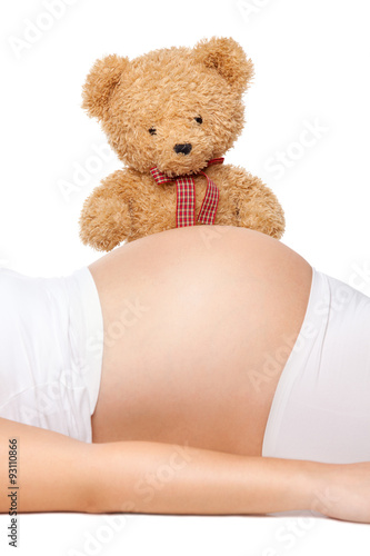 Teddy bear looking at belly of a pregnant woman