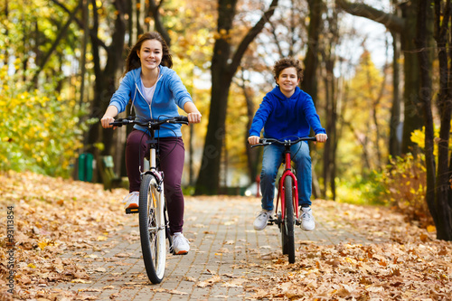 Urban biking - teens riding bikes in city park 