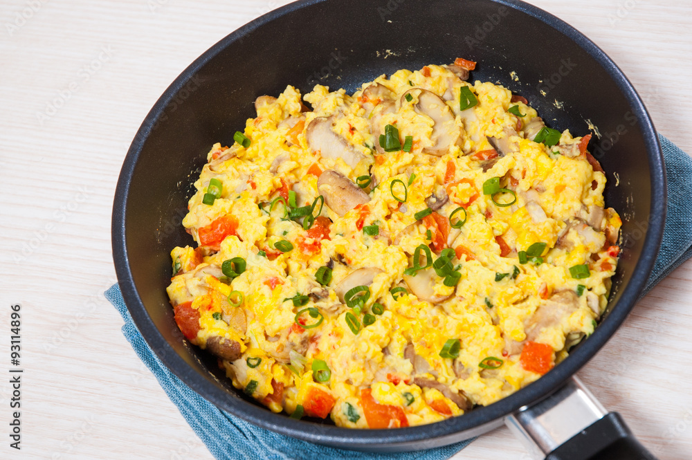 scrambled eggs with mushrooms and vegetables in a frying pan scrambled eggs with mushrooms and vegetables in a frying pan
