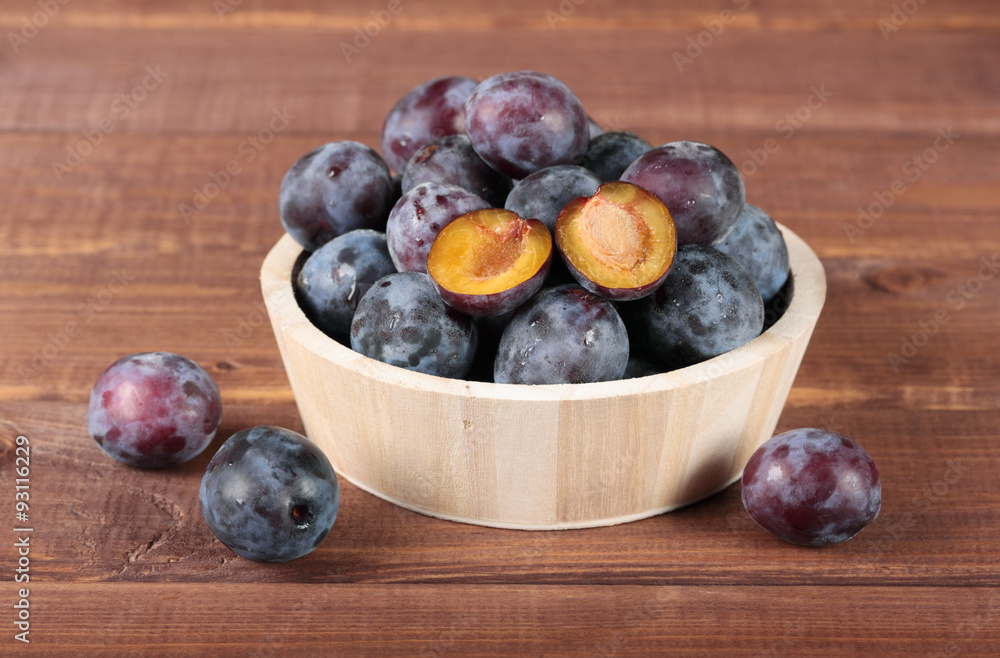 Fresh juicy plums in wooden round bowl Fresh juicy plums in wooden round bowl