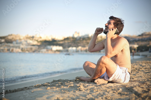 Happy man doing a phone call at the beach