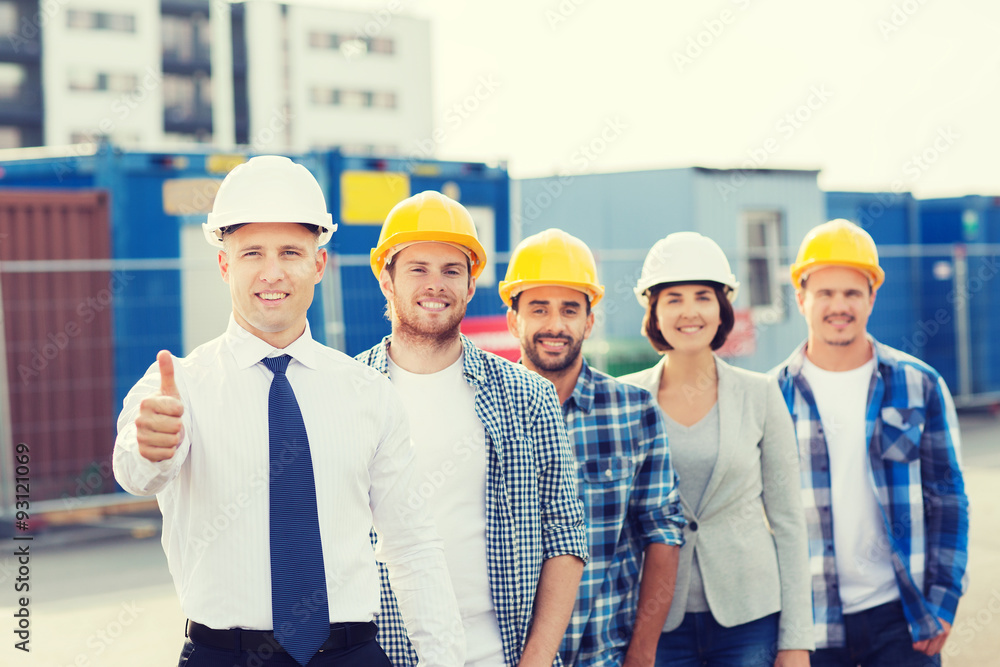 group of smiling builders in hardhats outdoors group of smiling builders in hardhats outdoors
