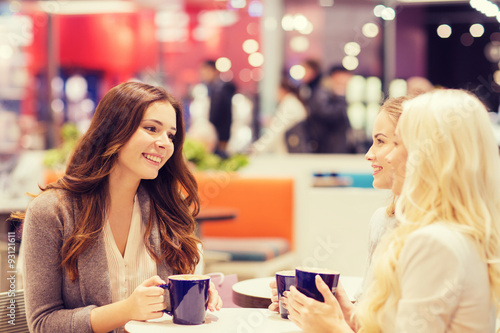 smiling young women drinking coffee in mall 