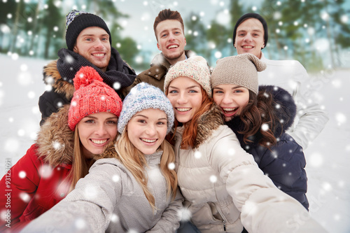 group of smiling friends taking selfie outdoors