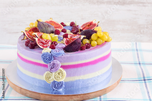 Violet and pink cake with fruit on white wooden background