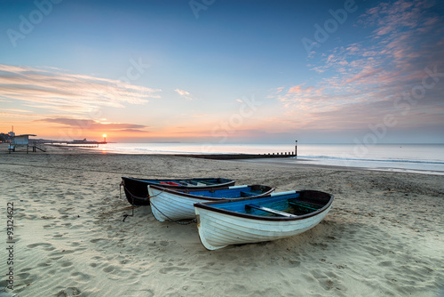 Valokuvatapetti Stunning sunrise over a row of fishing boats on Bournemouth beach in Dorset, wit