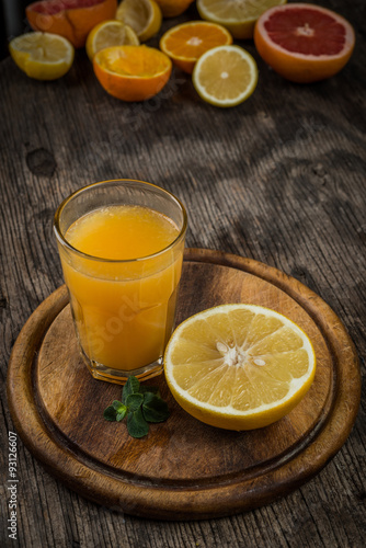 Citrus juice and fruits on vintage wooden background