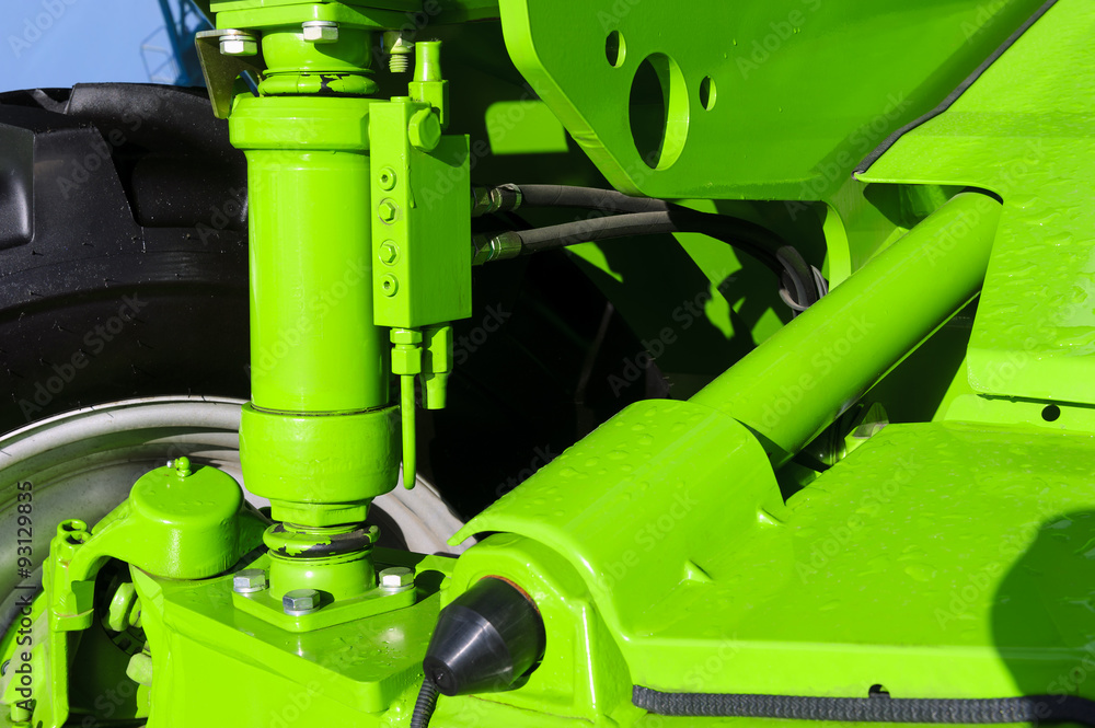 Naklejka premium Tractor hydraulic suspension and pneumatic piston system of modern big powerful construction machine with drops of rain on green vehicle bodywork, heavy industry 